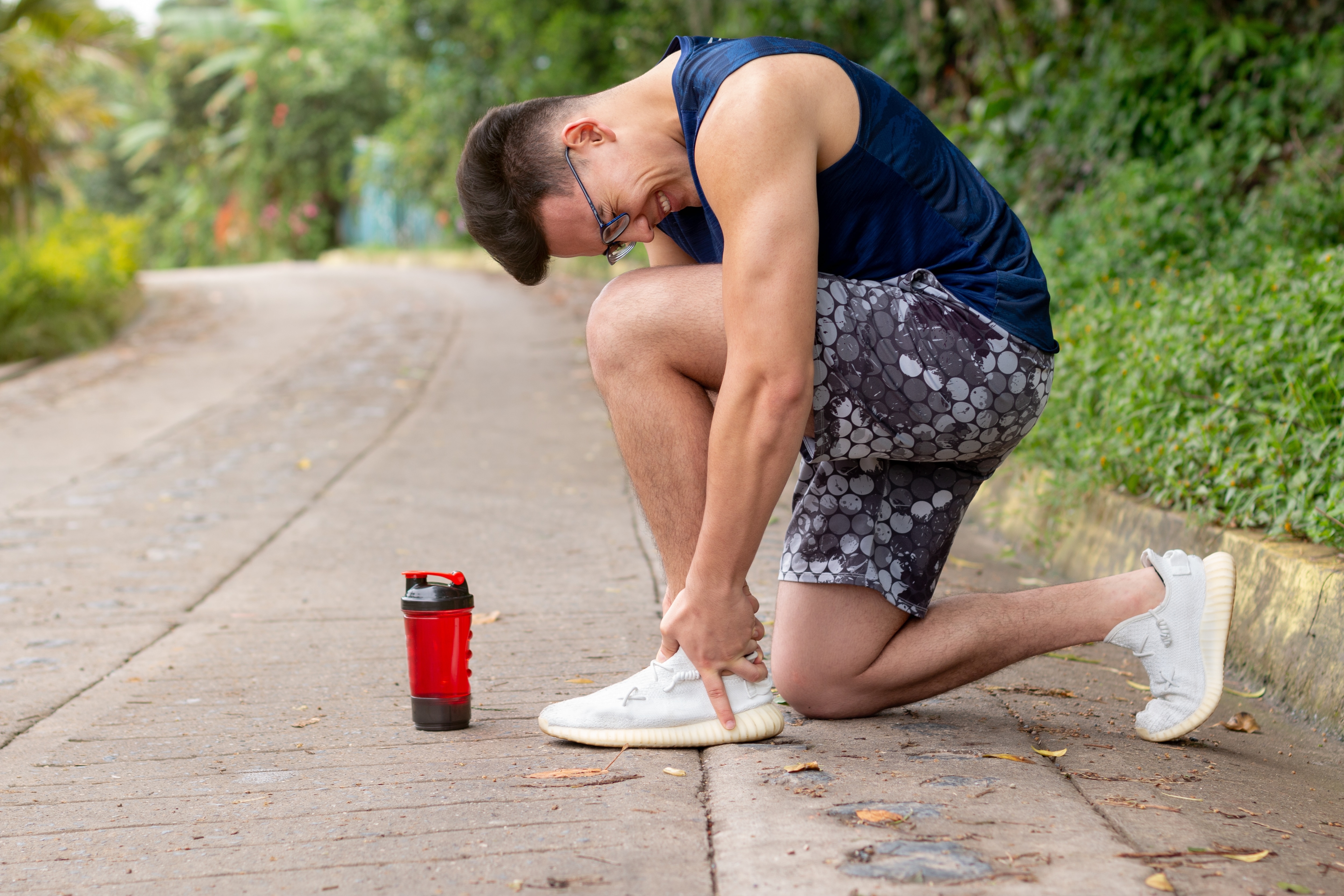 athlete holding ankle in pain after running