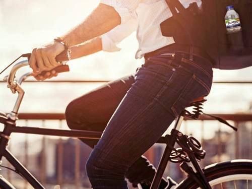 Man commuting on a bike with a Buxton Water bottle in his backpack