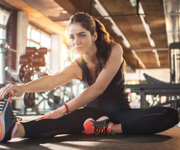 Woman stretching her hamstring whilst in the gym